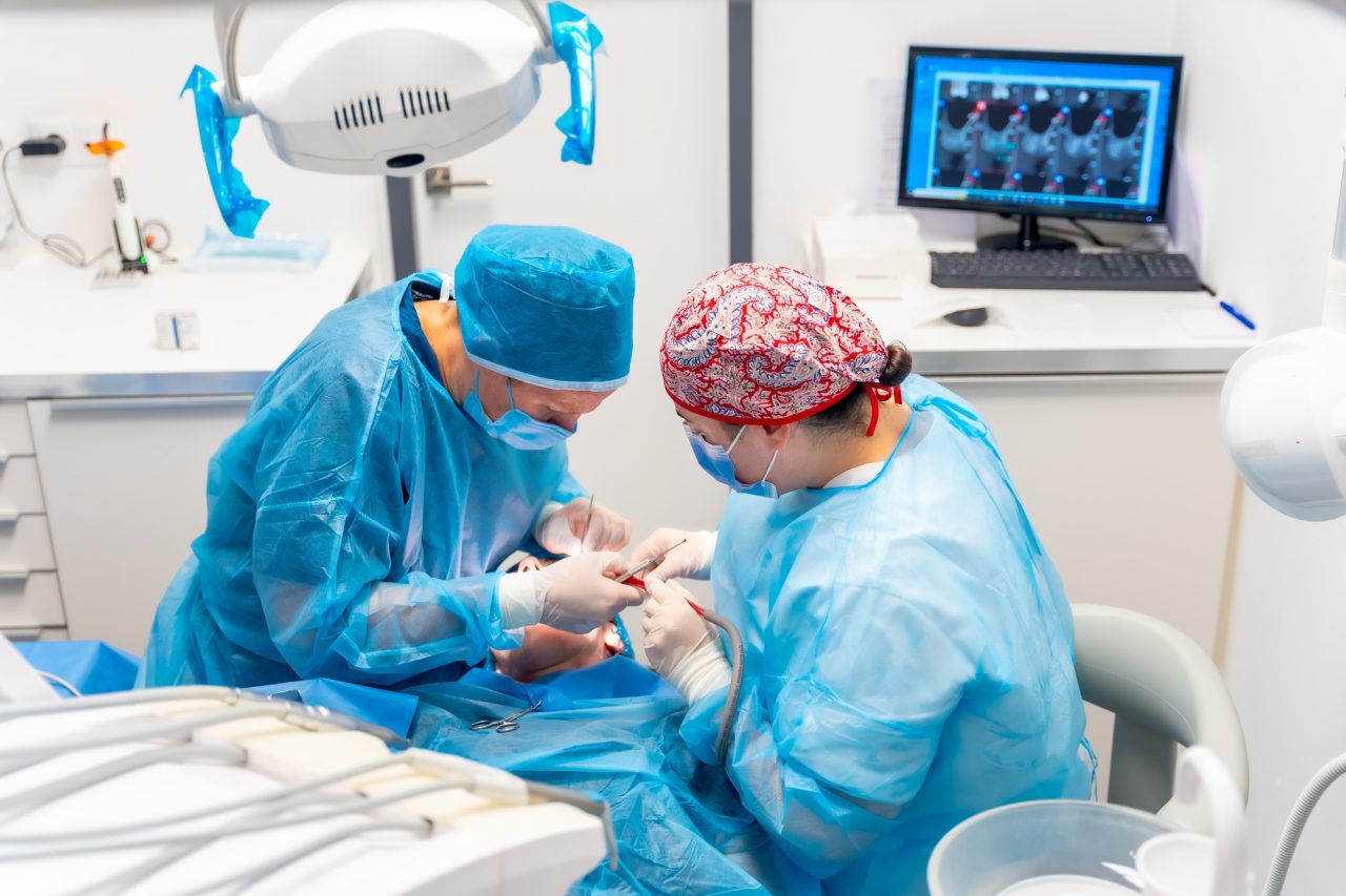 female-dentists-in-blue-scrubs-performing-a-complicated-operation-on-a-female-patient-sucking-blood.jpg